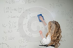 Caucasian woman erasing formulas from white board.