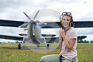 Caucasian woman on the field by a four-seater private jet in a pilot's suit.