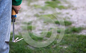 Caucasian woman gardener in the garden shows a rake. The concept of gardening and sustainable summer. Woman`s hand with a garden