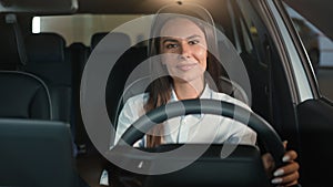 Caucasian woman girl female driver sitting in rental car inside in automobile smiling happy at camera driving enjoy