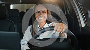 Caucasian woman girl female driver sitting in rental car inside in automobile smiling happy at camera driving enjoy