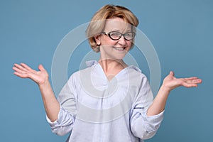 Caucasian woman in glasses and casual clothes shrugging her shoulders.