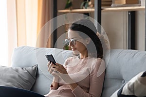 Caucasian woman in glasses using cellphone at home