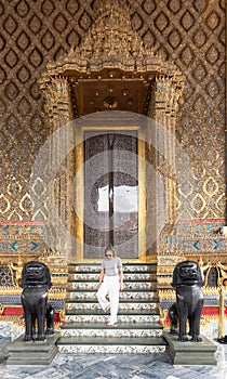 Caucasian woman going down on the marble stairs of the Wat Phra Kaew Temple, Bangkok, Thailand