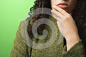 Caucasian woman with hand on chin wearing green clothing.