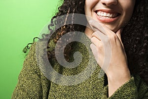 Caucasian woman with hand on chin wearing green clothing.