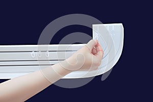 A Caucasian woman hand puts plastic hooks on white curtain rod. Dark blue background