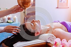 Caucasian woman having Ayurveda shirodhara treatment photo