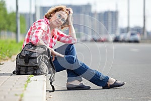 Caucasian woman hitch a ride, alone traveler sitting on roadside and waiting the car