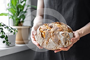 caucasian woman holding fresh bread from the oven, baking homemade bread