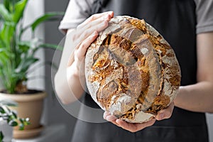 caucasian woman holding fresh bread from the oven, baking homemade bread