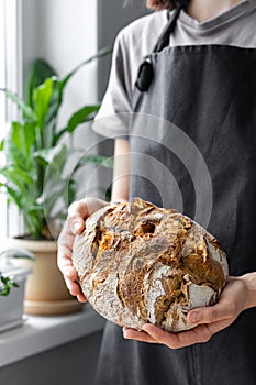 caucasian woman holding fresh bread from the oven, baking homemade bread