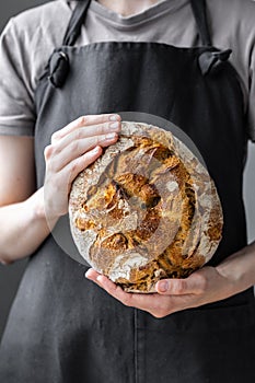 caucasian woman holding fresh bread from the oven, baking homemade bread