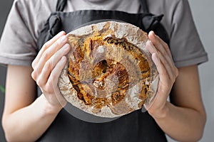 caucasian woman holding fresh bread from the oven, baking homemade bread