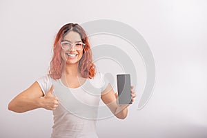 Caucasian woman holding phone with blank screen and showing thumb up on white background.