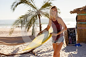 Caucasian woman holding surf board on beach
