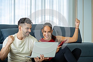 Caucasian woman with husband work from home with laptop notebook and cellular phone in living room. social