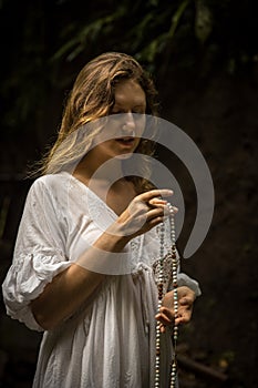 Caucasian woman keeping count during pray and meditation. Buddhist japa mala. Strands of gemstones beads. Religion concept.