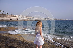 Caucasian woman looking towards the ocean, and the tourist resort known as Las Americas, Costa Adeje, Tenerife, Canary Islands