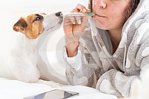 Caucasian woman lying in bed and measures the temperature orally. Girl holding a mercury thermometer in her mouth