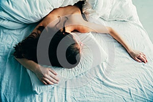 Caucasian woman lying in bed sleeping, her messy hair on pillow