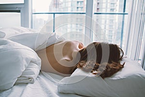 Caucasian woman lying in bed sleeping, her messy hair on pillow