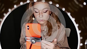 Caucasian woman makeup artist applies eyeshadow sitting in front of ring light