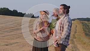 Caucasian woman and man family mother father with daughter stands in wheat field looks at horizon landscape dreaming