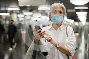 Caucasian woman in mask with smartphone in subway station