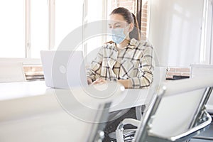 Caucasian woman with medical mask for coronavirus covid-19 protection working in office, new normal business practise of