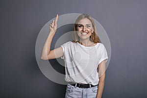 Caucasian woman in neutral casual outfit standing on a neutral grey background. Portrait with emotions: happiness, amazement, joy