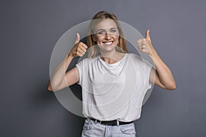 Caucasian woman in neutral casual outfit standing on a neutral grey background. Portrait with emotions: happiness, amazement, joy