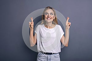 Caucasian woman in neutral casual outfit standing on a neutral grey background. Portrait with emotions: happiness, amazement, joy