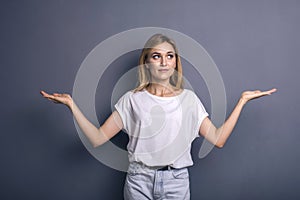 Caucasian woman in neutral casual outfit standing on a neutral grey background. Portrait with emotions: happiness, amazement, joy