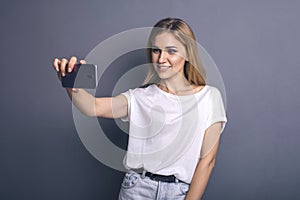 Caucasian woman in neutral casual outfit standing on a neutral grey background. Portrait with emotions: happiness, amazement, joy