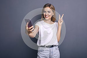 Caucasian woman in neutral casual outfit standing on a neutral grey background. Portrait with emotions: happiness, amazement, joy