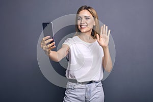 Caucasian woman in neutral casual outfit standing on a neutral grey background. Portrait with emotions: happiness, amazement, joy