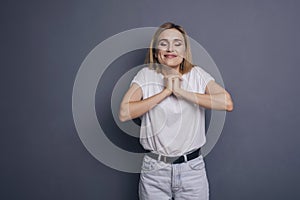 Caucasian woman in neutral casual outfit standing on a neutral grey background. Portrait with emotions: happiness, amazement, joy