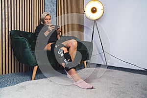 Caucasian woman patient with bandage compression knee brace support injury on the sofa holding a phone.healthcare and