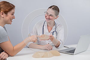 Caucasian woman and plastic surgeon touching and choosing breast implants.