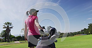Caucasian woman playing golf carrying bag filled with golf clubs
