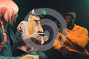 Caucasian woman playing video games, Afro-American man and Asian young woman talking medium shot