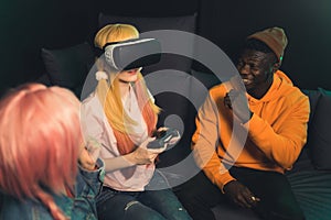 Caucasian woman playing with vr goggles, Afro-American man and Asian young woman sitting beside medium shot multi-ethnic