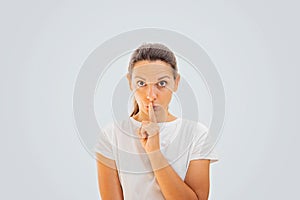 Caucasian woman portrait doing silence gesture with finger. White color. Censorship concept