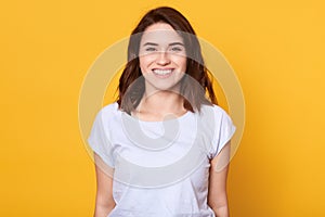 Caucasian woman posing isolated over yellow background, woman with charming smile looking happy directly at camera, adorable girl