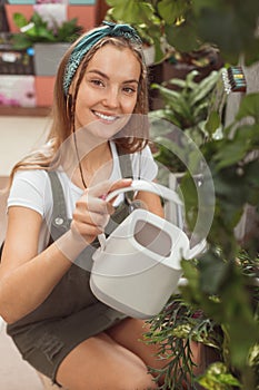 Caucasian woman is pouring water in plants. Watering houseplants in greenhouse store