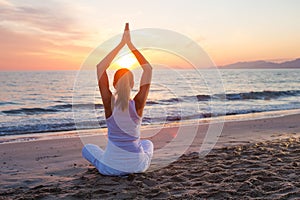 Caucasian woman practicing yoga at seashore