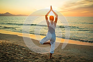 Caucasian woman practicing yoga at seashore