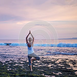 Caucasian woman practicing yoga at seashore