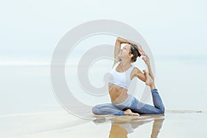 Caucasian woman practicing yoga at seashore